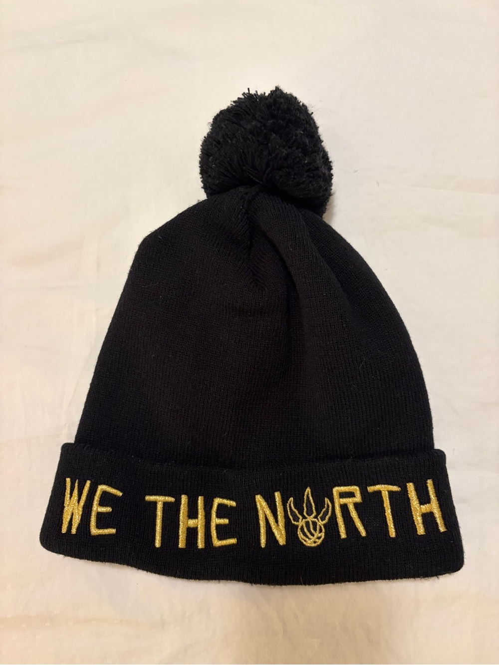Toronto Raptors Black Pom Beanie with Gold 'WE THE NORTH' Embroidery